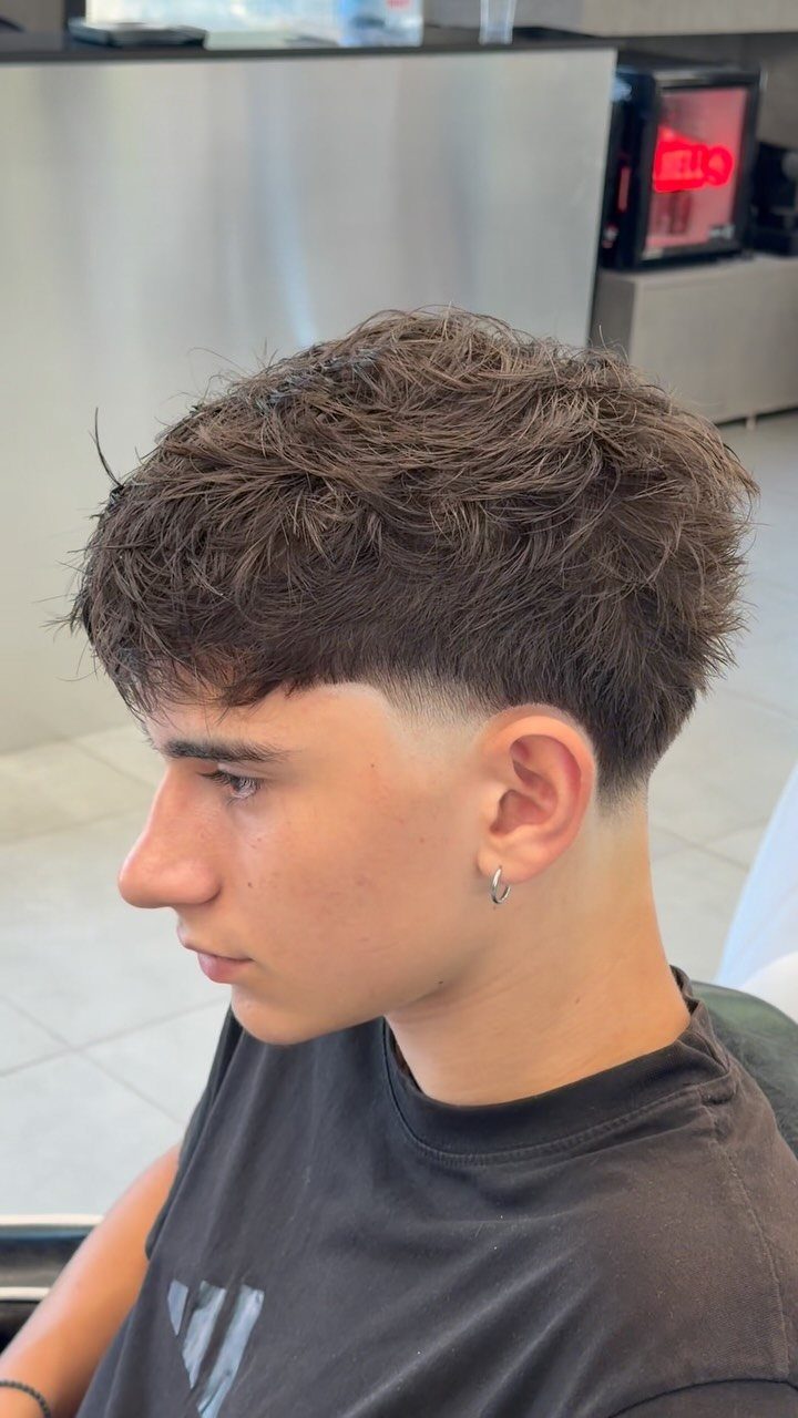 Young man with a textured fringe haircut and a low taper fade.