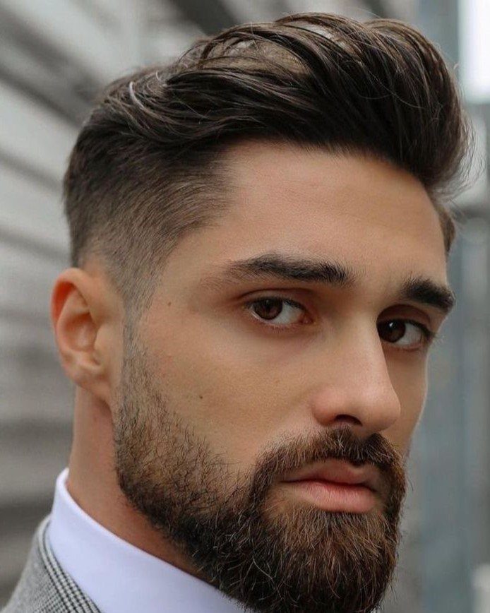 Man with medium length brown hair styled up and a groomed beard.