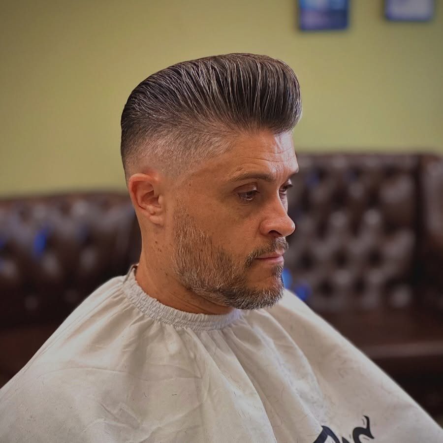 Man with a high volume classic pompadour haircut and groomed beard in barbershop