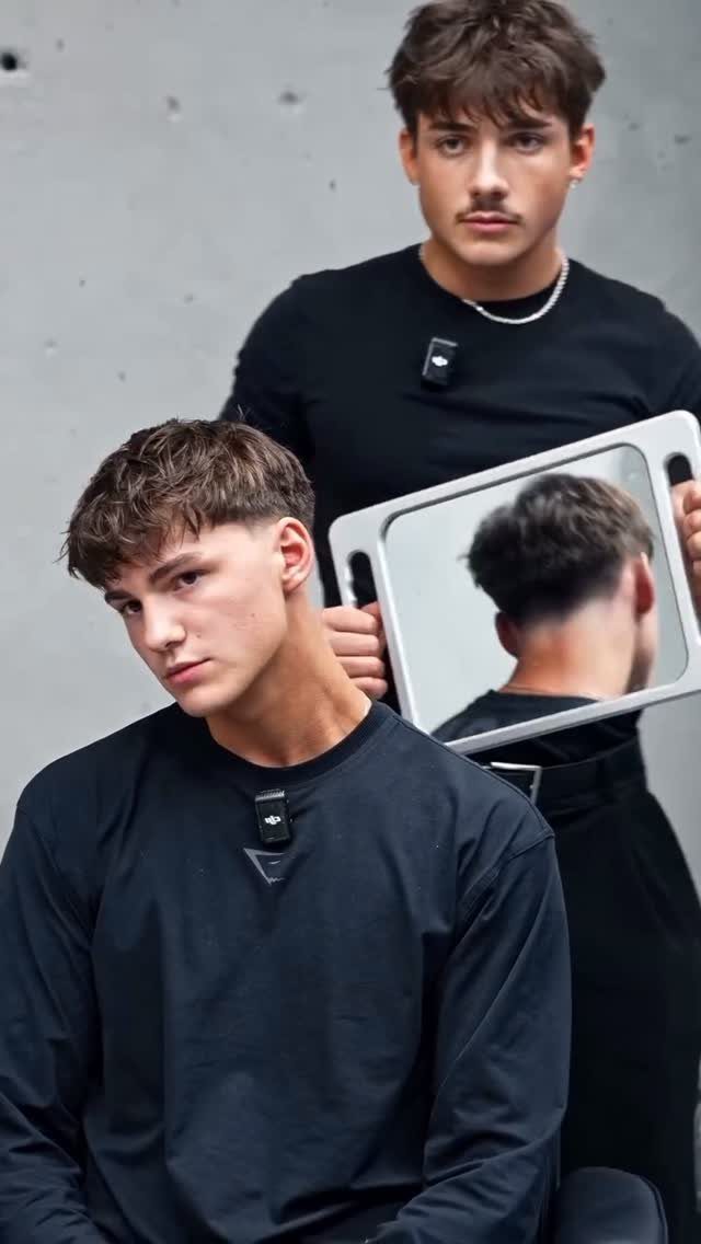 Young man with a textured messy fringe haircut wearing a black shirt.