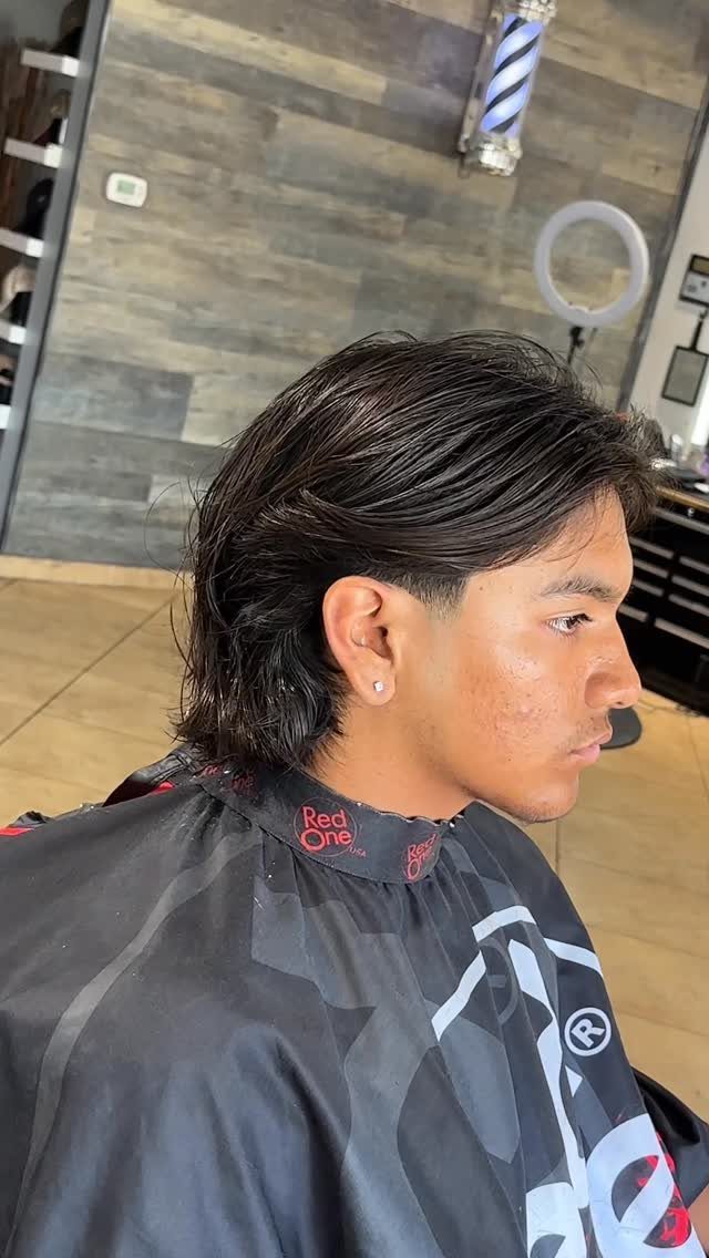 Young man with a modern mullet haircut, slicked back top and longer back.