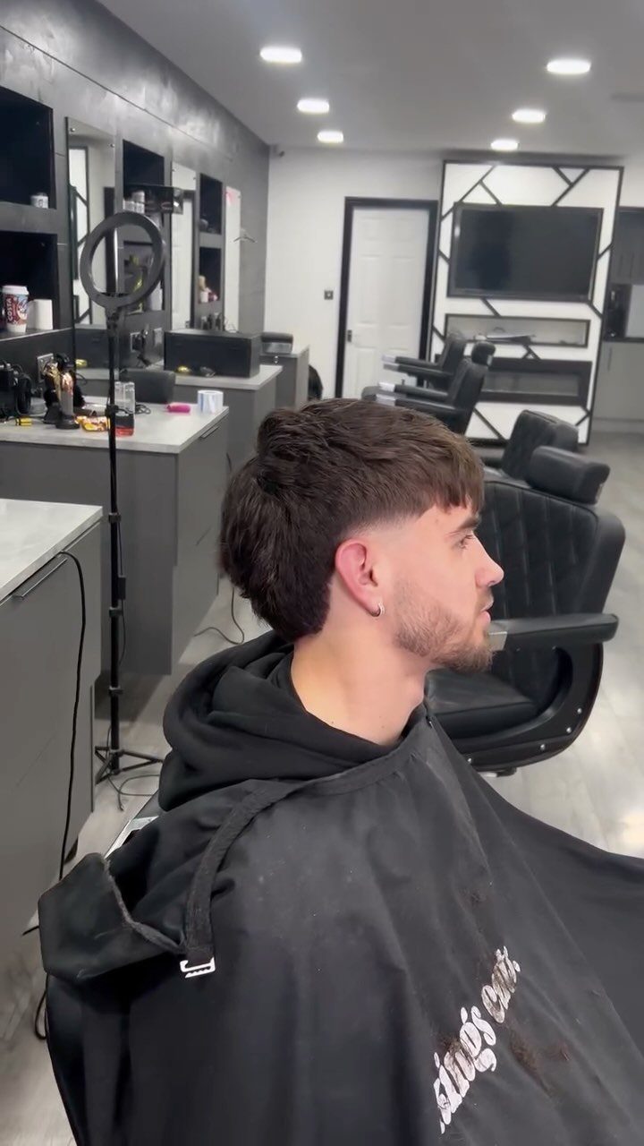 Man with a natural taper haircut sitting in a professional barbershop chair.