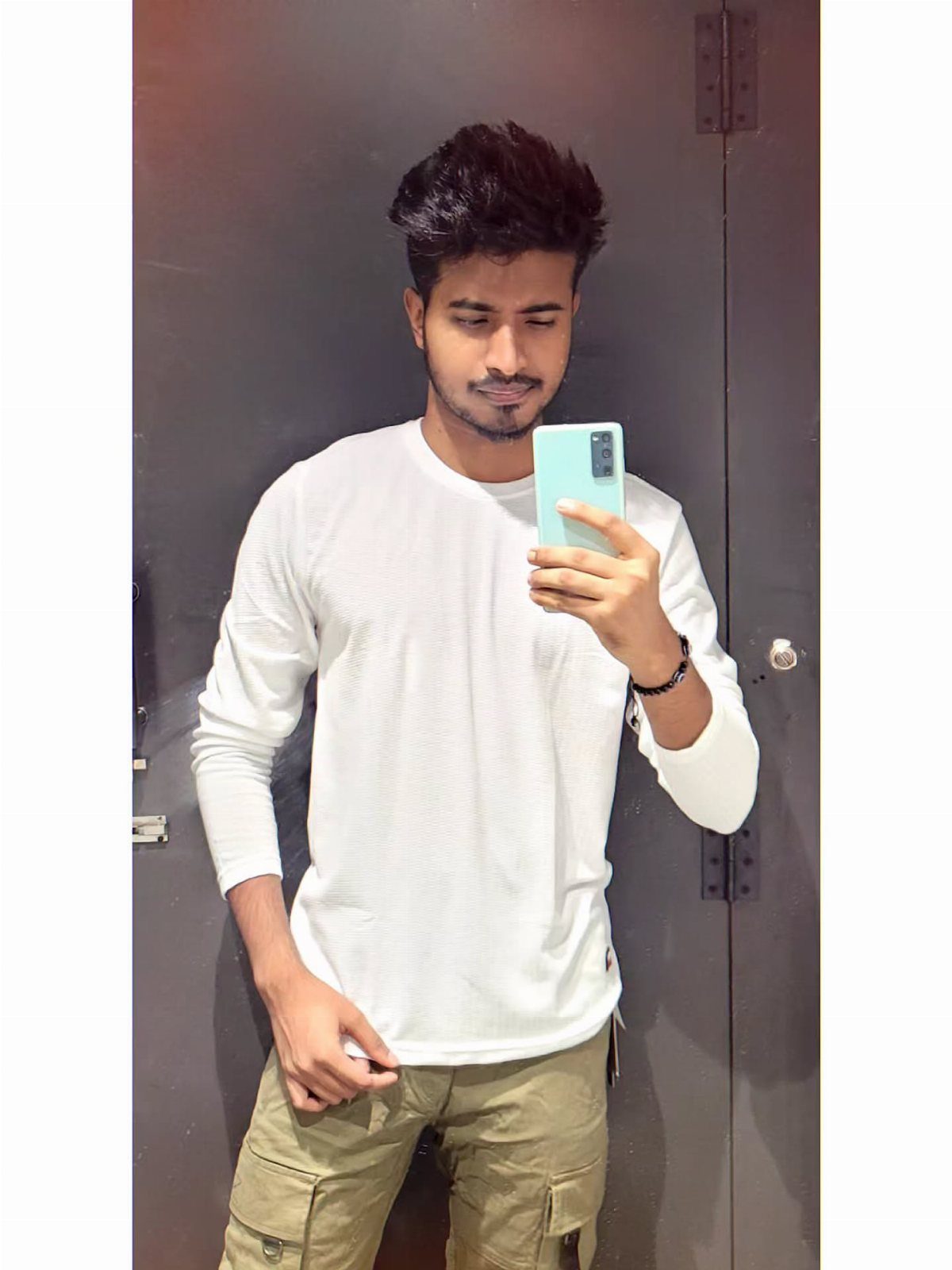 Young man with voluminous medium length dark hair taking a mirror selfie