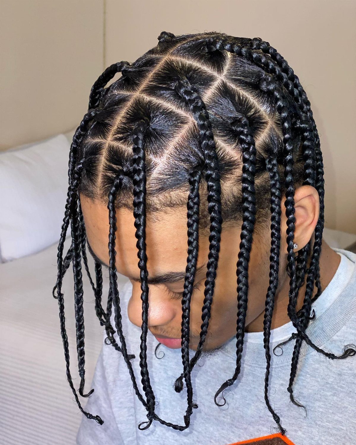 Man with black hair styled in neat, medium-length individual braids hanging down.