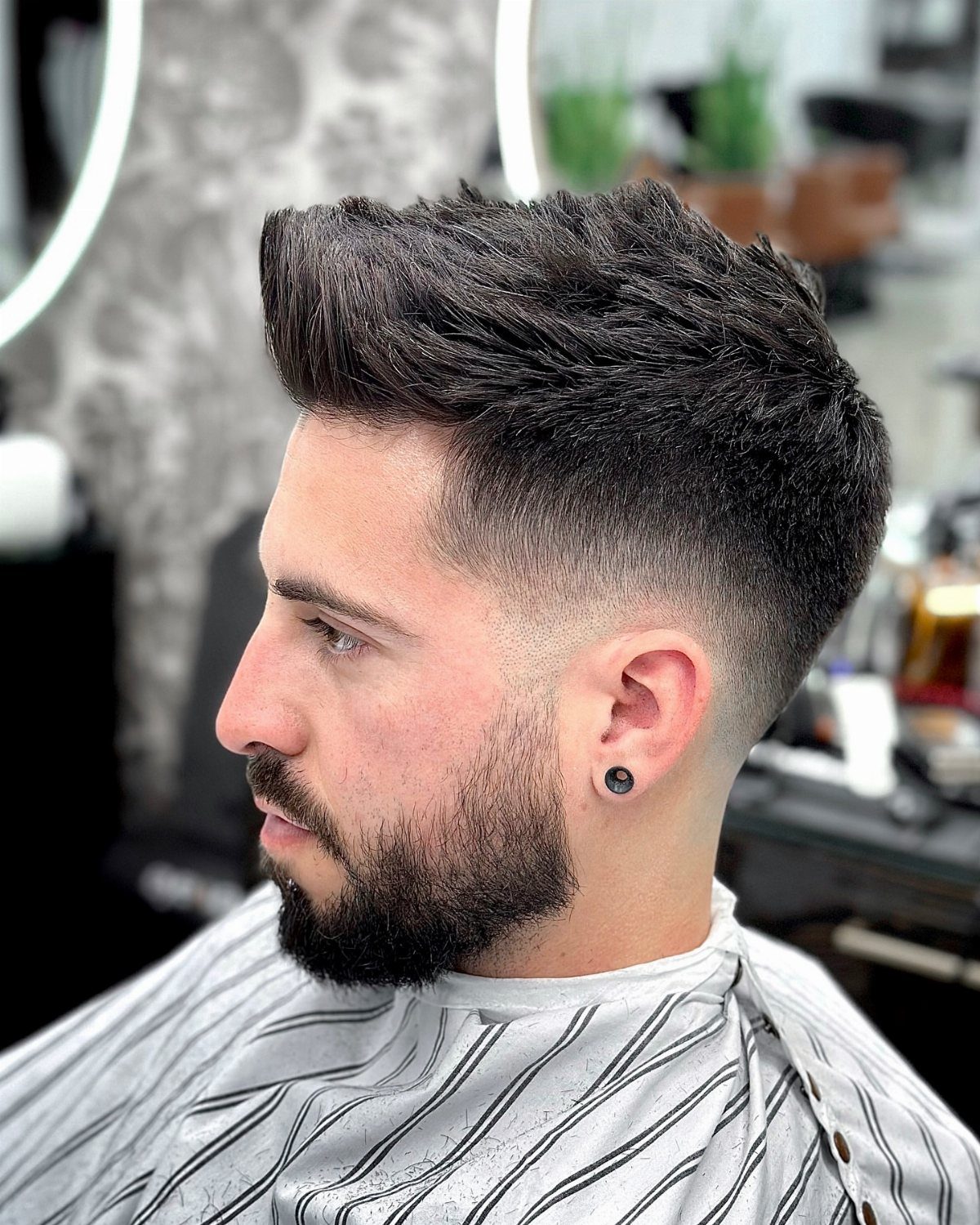Man with a faux hawk haircut, skin fade, and a groomed dark beard.