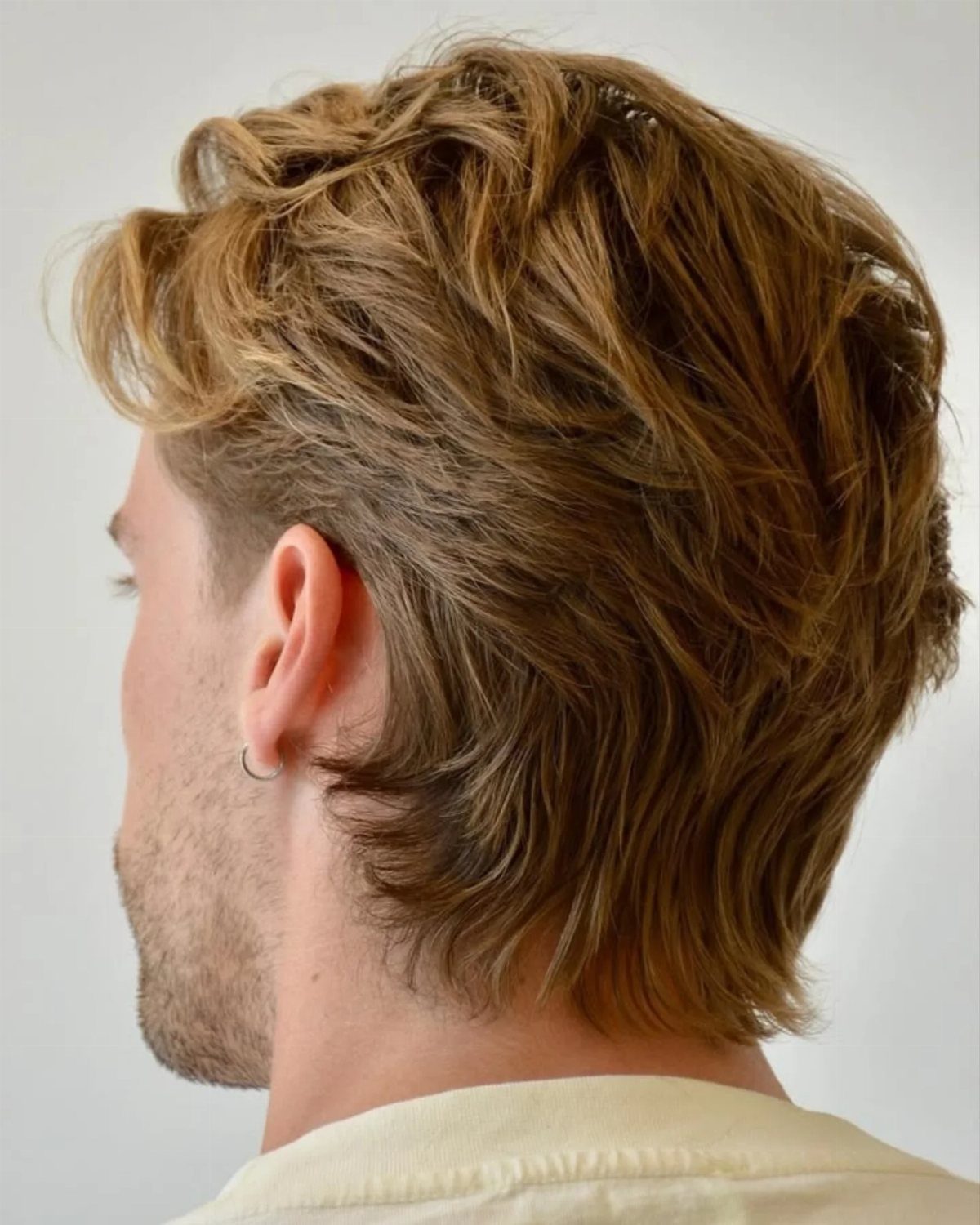 Man with medium-length layered light brown hair styled with volume and texture.