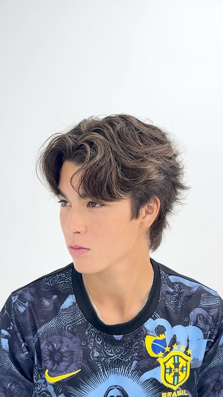 Young man with brown medium length hair styled in a middle part.