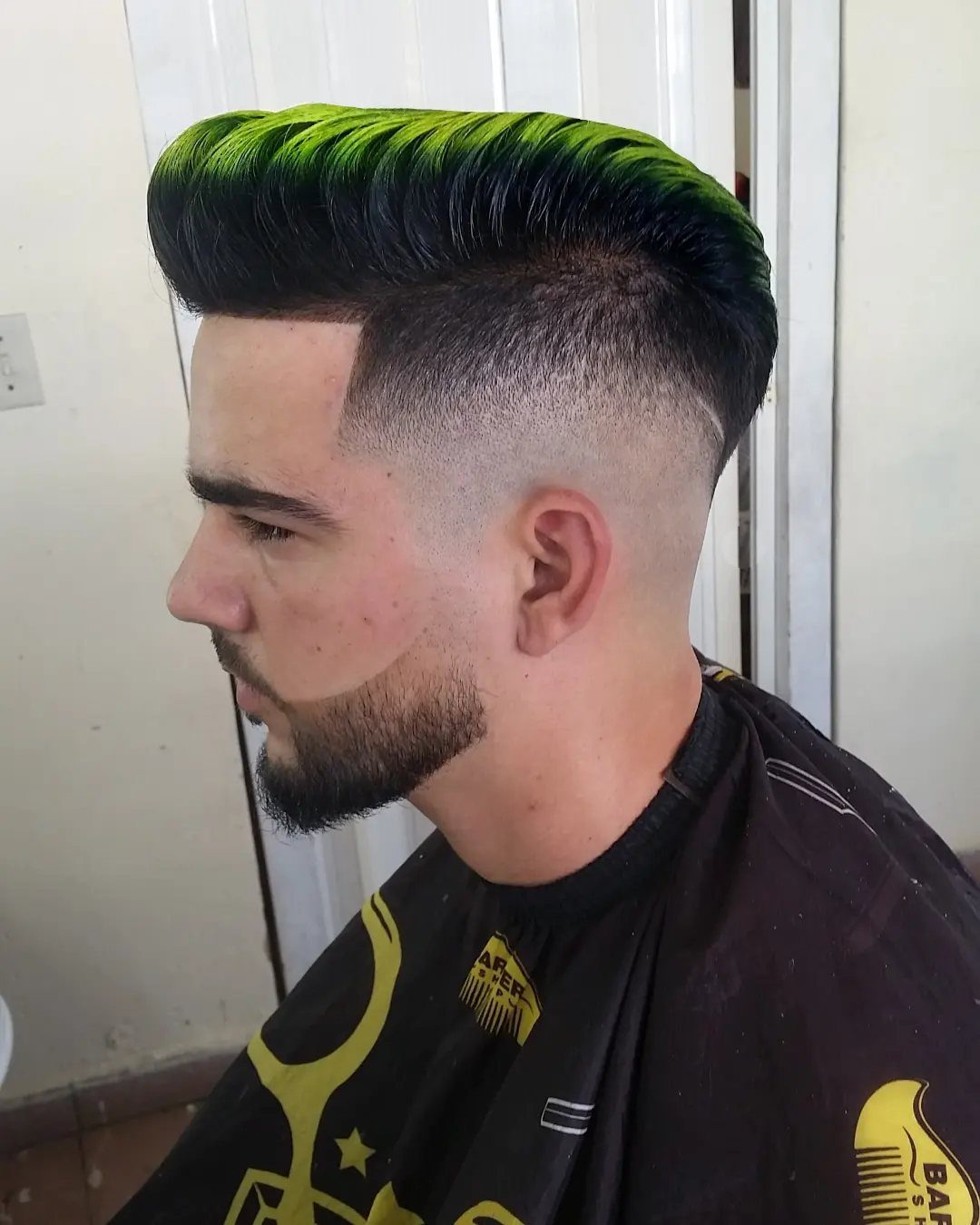 Man with a neon green pompadour hairstyle and a high skin fade haircut.