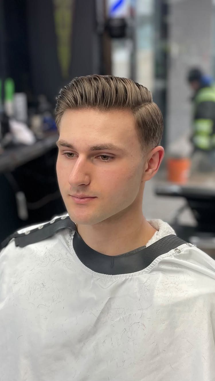 Man with brown medium-length hair styled in a classic side part and combed back.