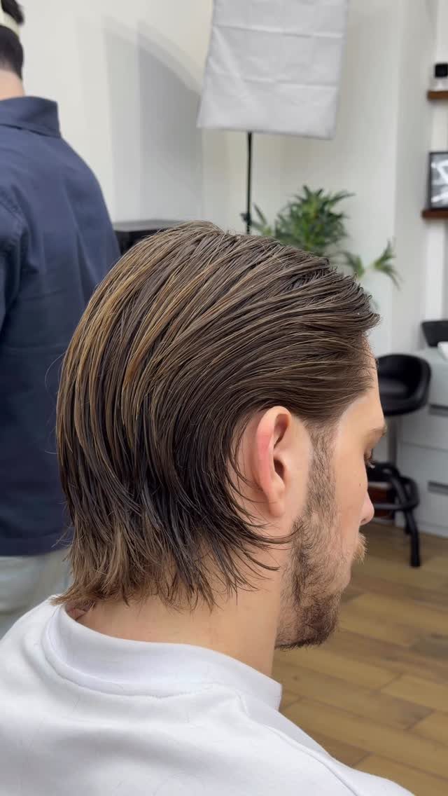 Man with medium-length brown hair slicked back and a short groomed beard.