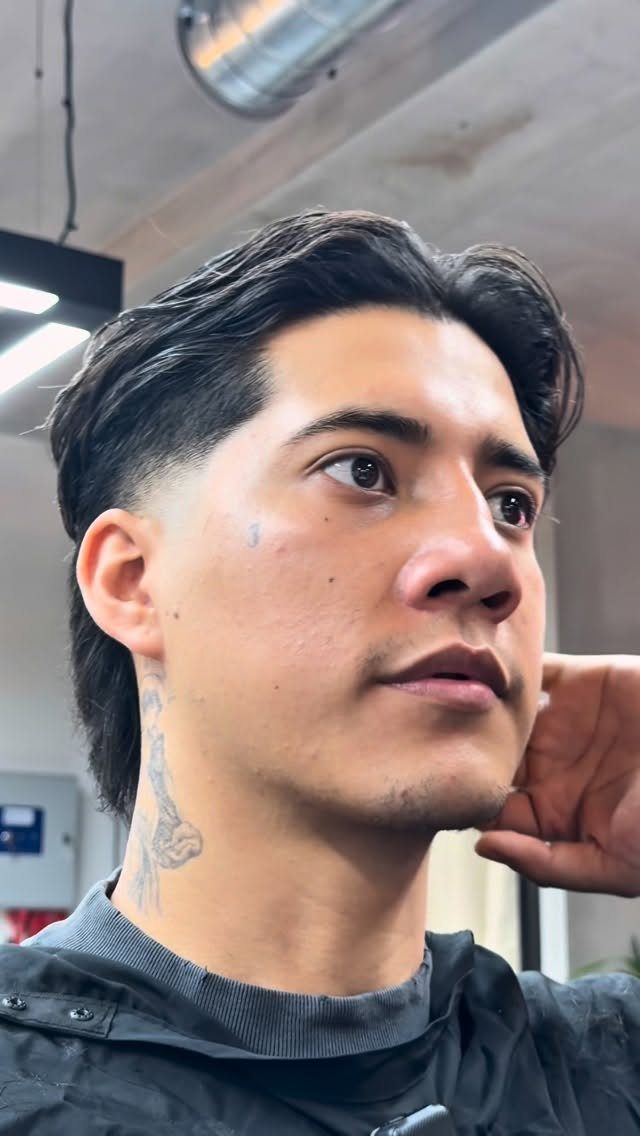 Man with a dark undercut hairstyle, long top swept back and shaved sides.