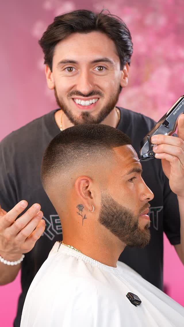 Man with a buzz cut fade and groomed beard getting a haircut from a barber.