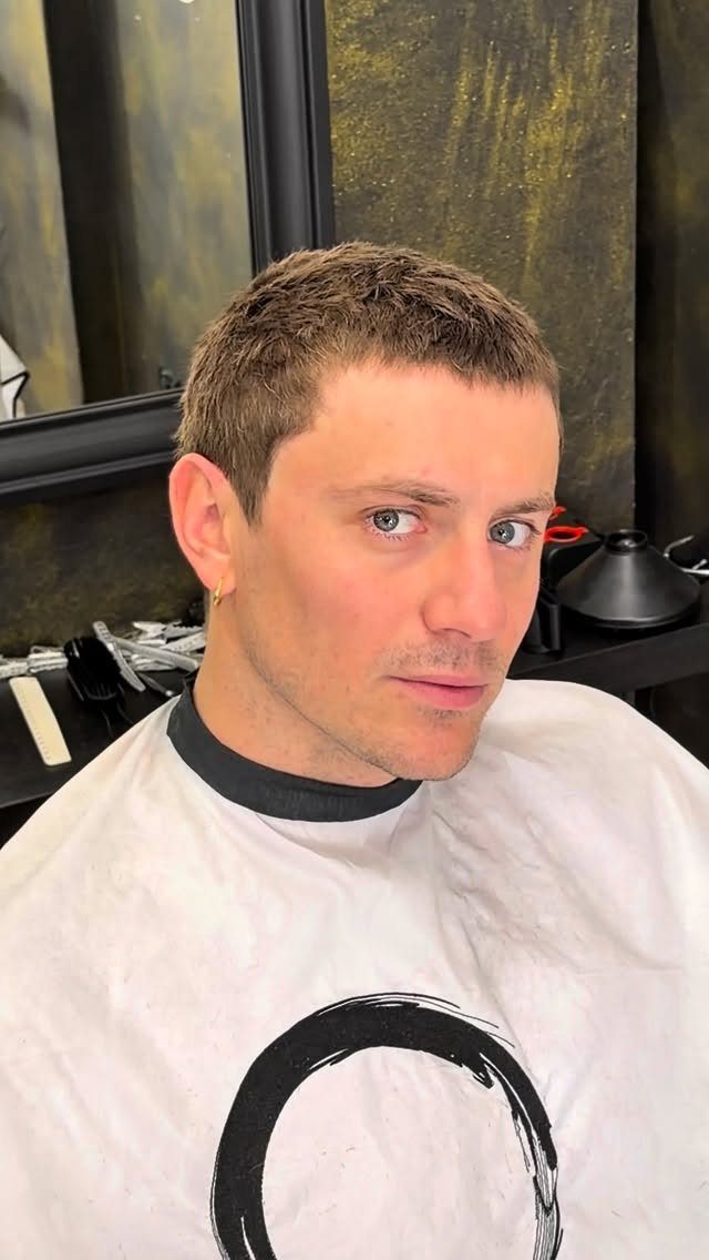 Man with a short classic buzz cut wearing a white barber cape.