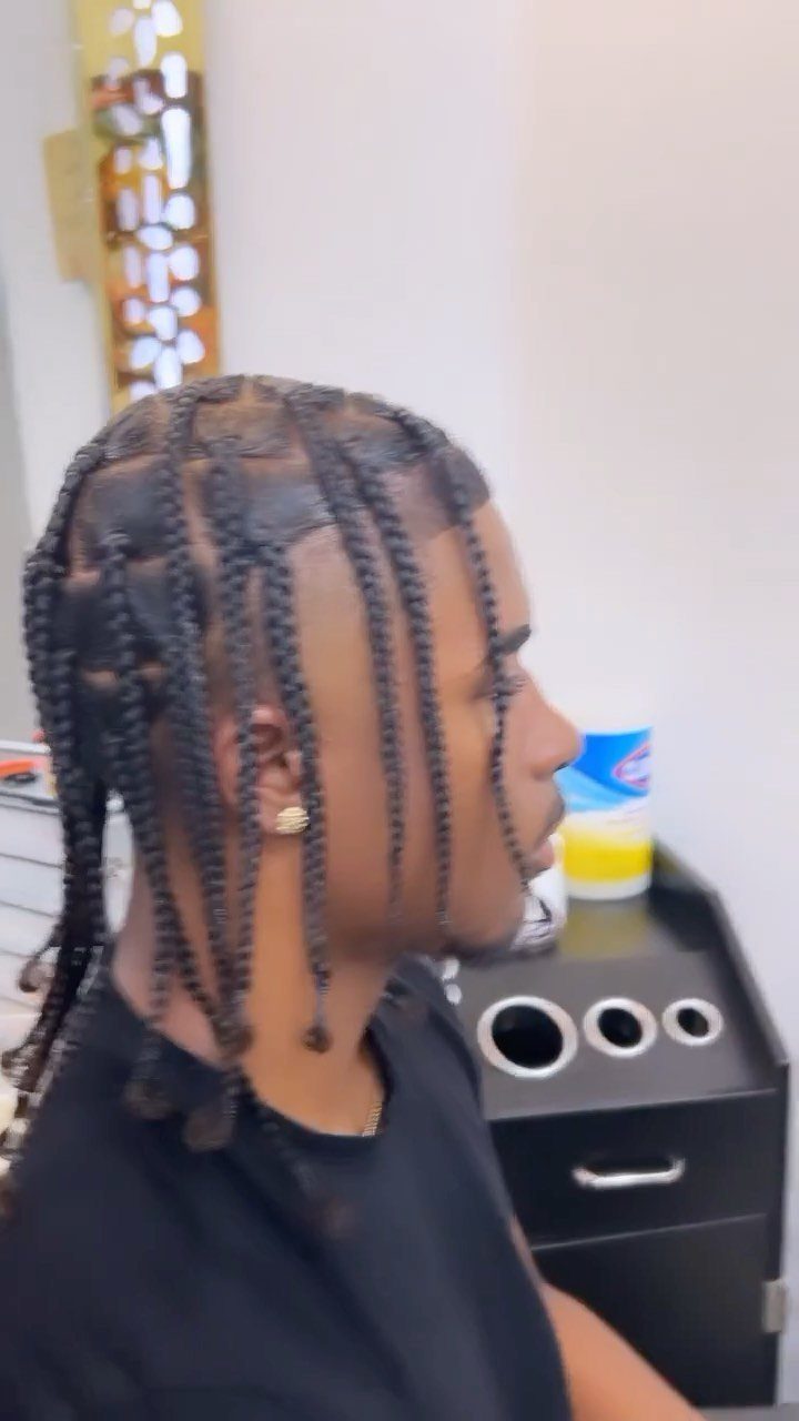Black man with box braids parted into square sections in a side profile view.