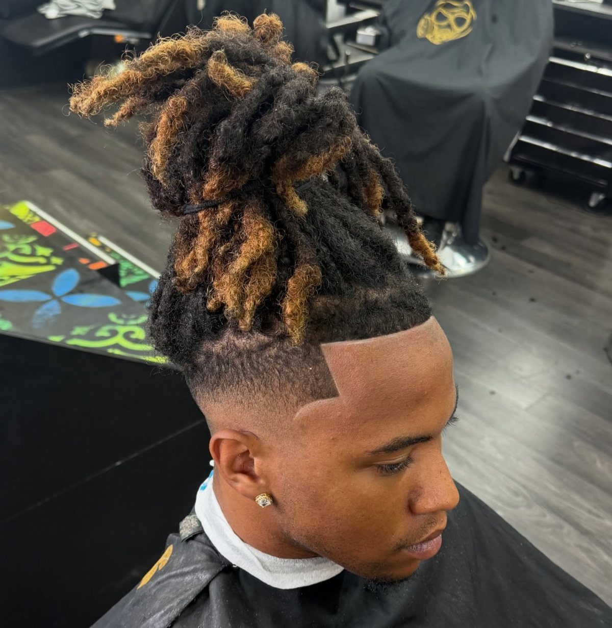 Man with long locs tied up and a sharp clean line-up haircut fade.