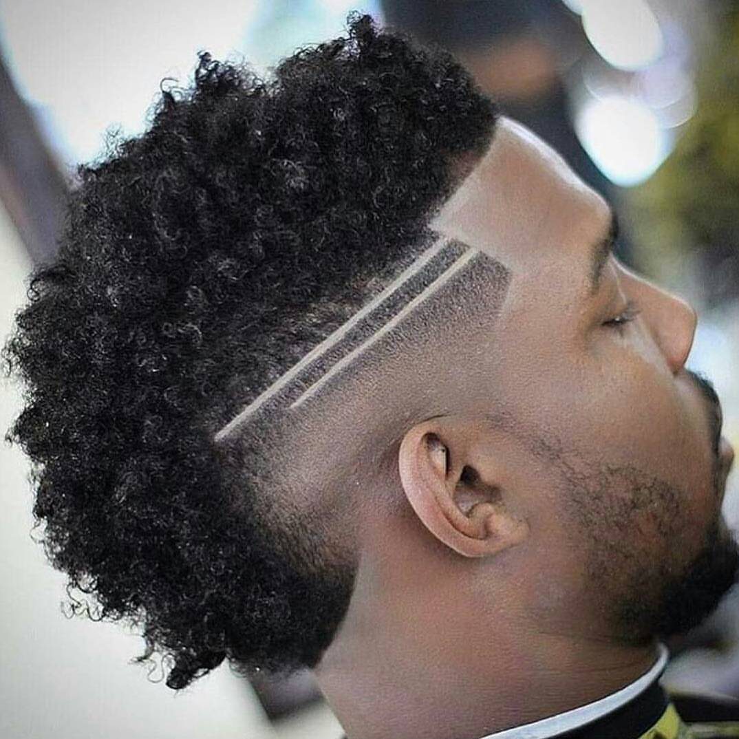 Man with a frohawk featuring curly hair and shaved sides with carved lines.