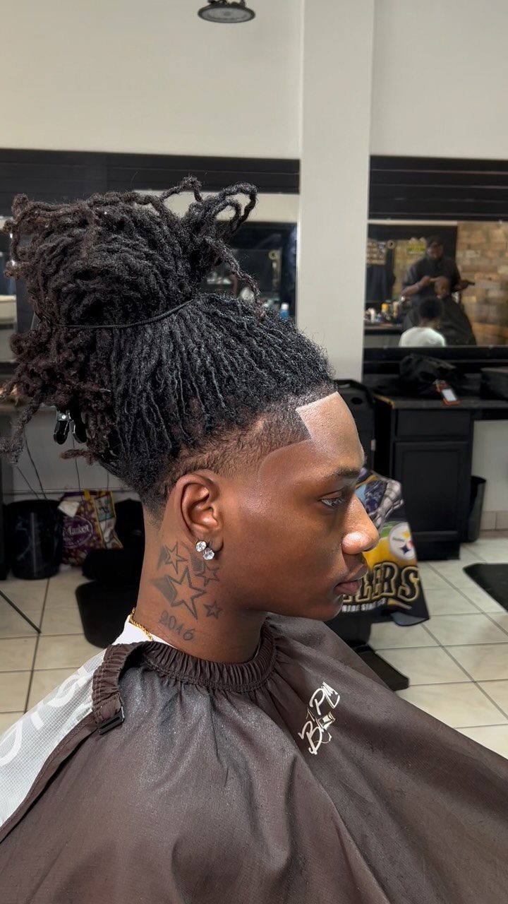Man with long locs tied in a ponytail and a clean side fade.