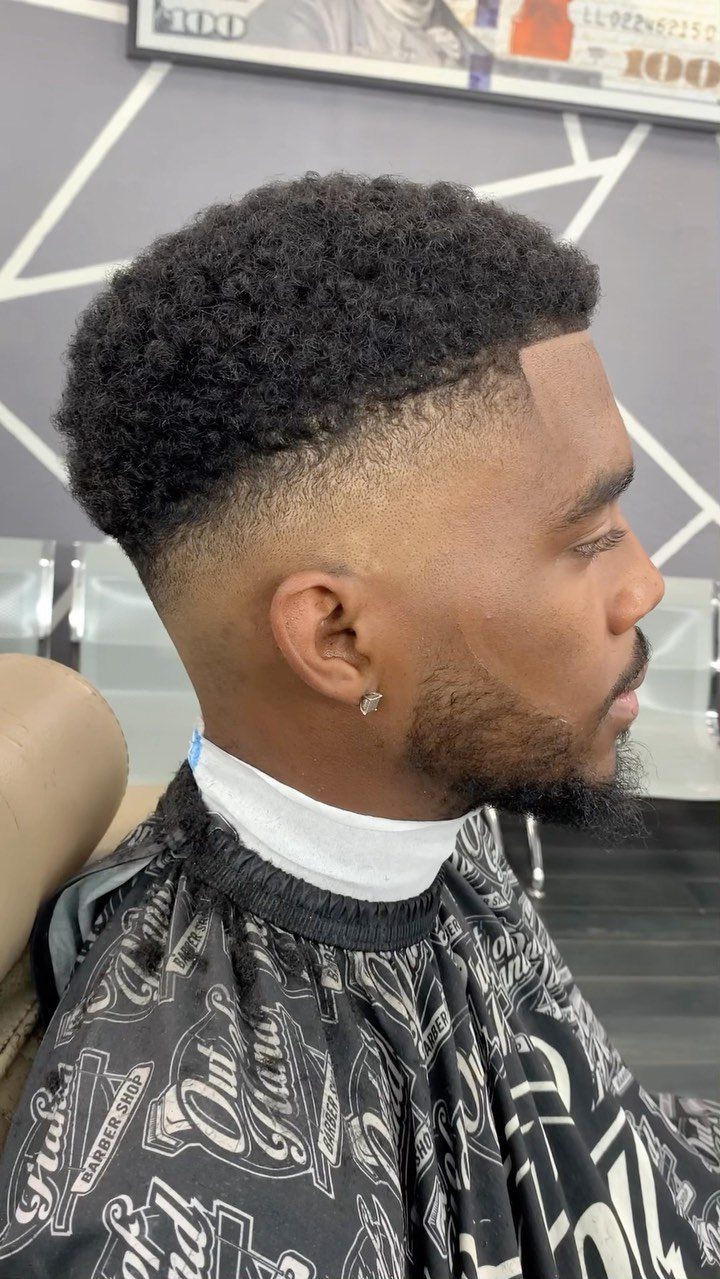 Black man with a short textured afro and a low taper fade haircut.