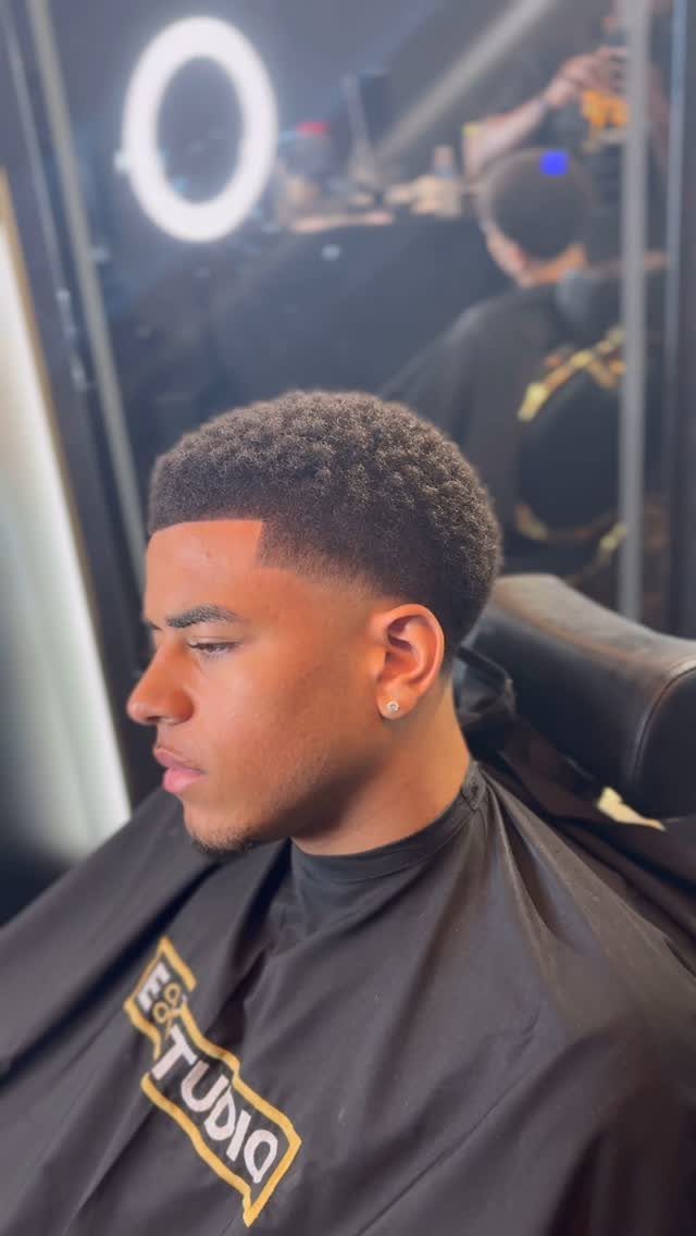 Young Black man with a short afro and a clean fade haircut.