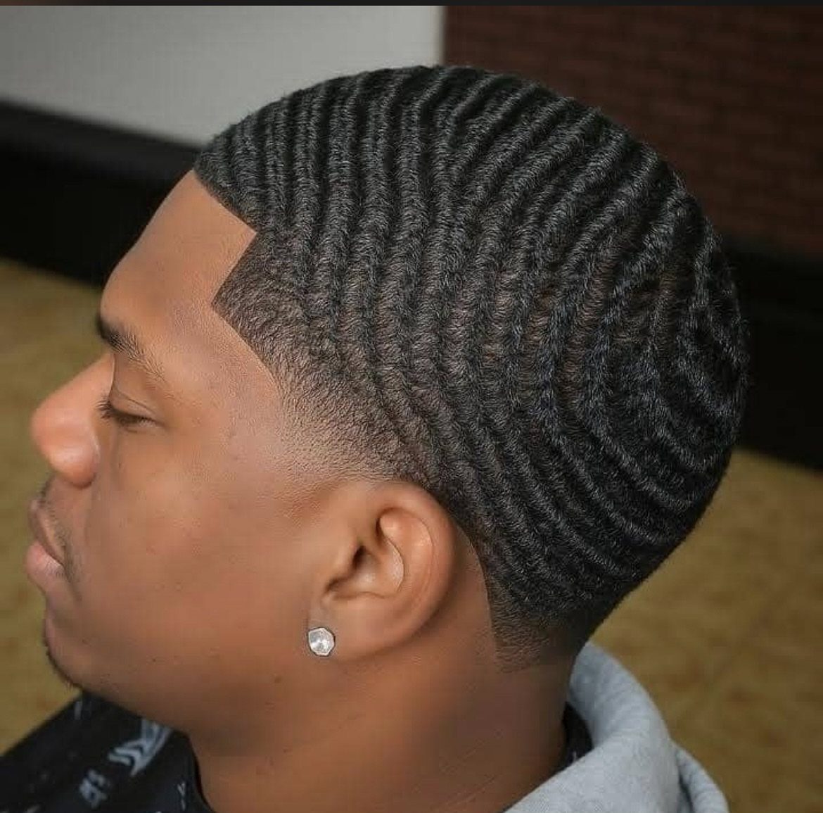 Black man with a skin fade haircut and deep 360 waves on top.