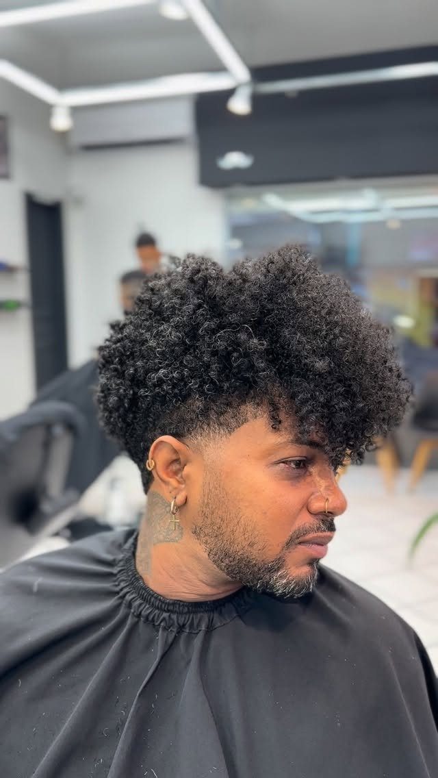 Man with a voluminous tapered afro and short beard in a barbershop