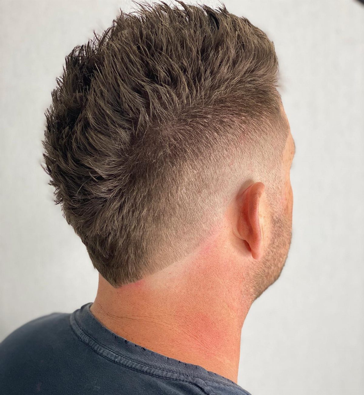 Man with a brown faux hawk haircut and faded sides in profile view.