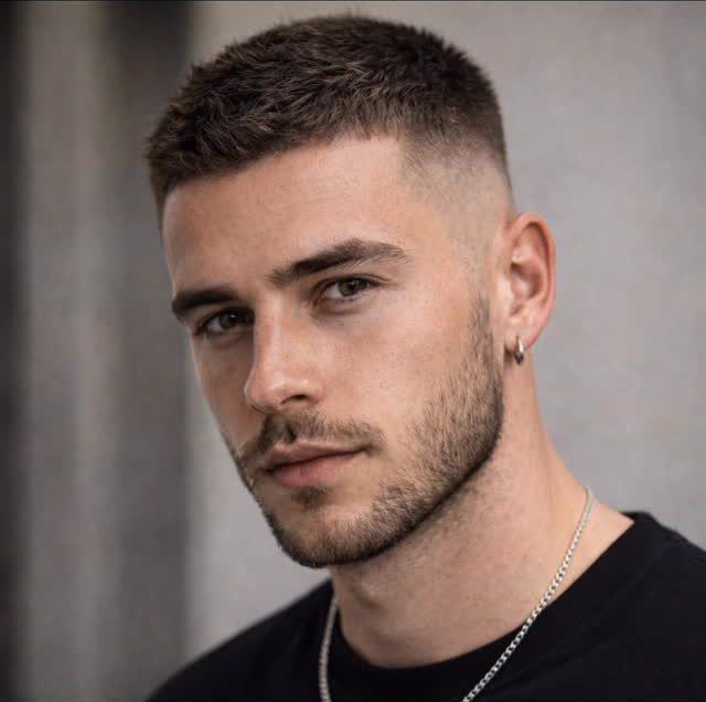 Man with a textured short haircut and a mid fade on the sides.