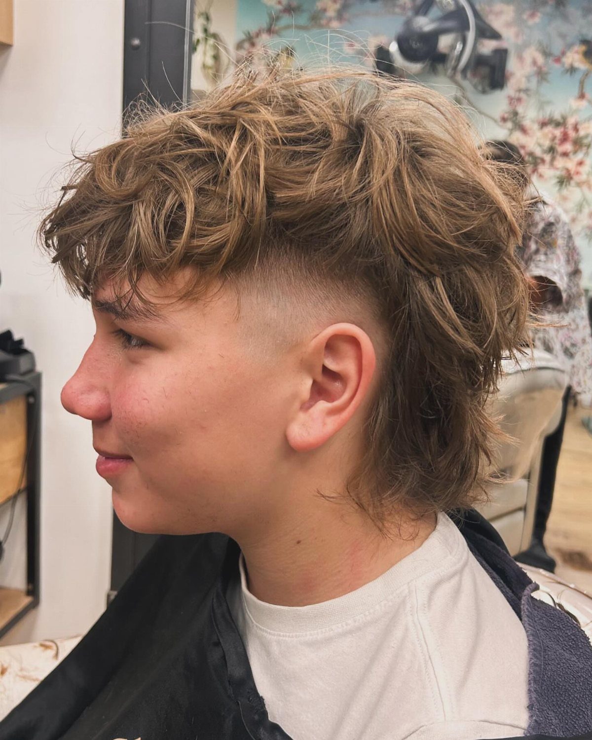 Young man with a modern mullet haircut featuring shaved sides and long back.