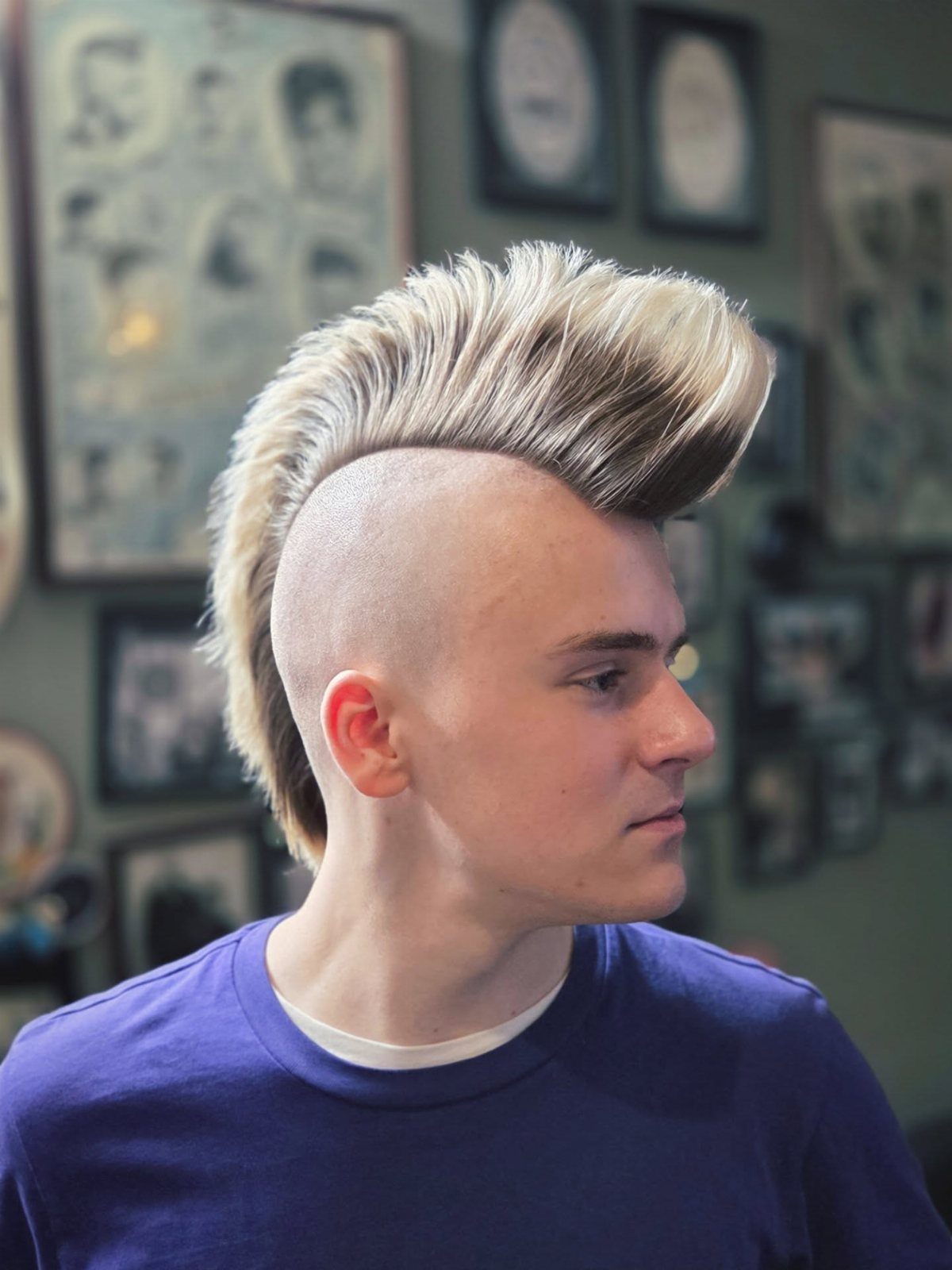 Young man with a styled blonde mohawk and shaved sides in a barbershop