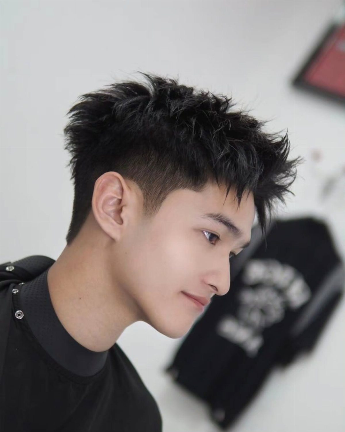 Young man with a short, spiky textured haircut and faded sides in profile.
