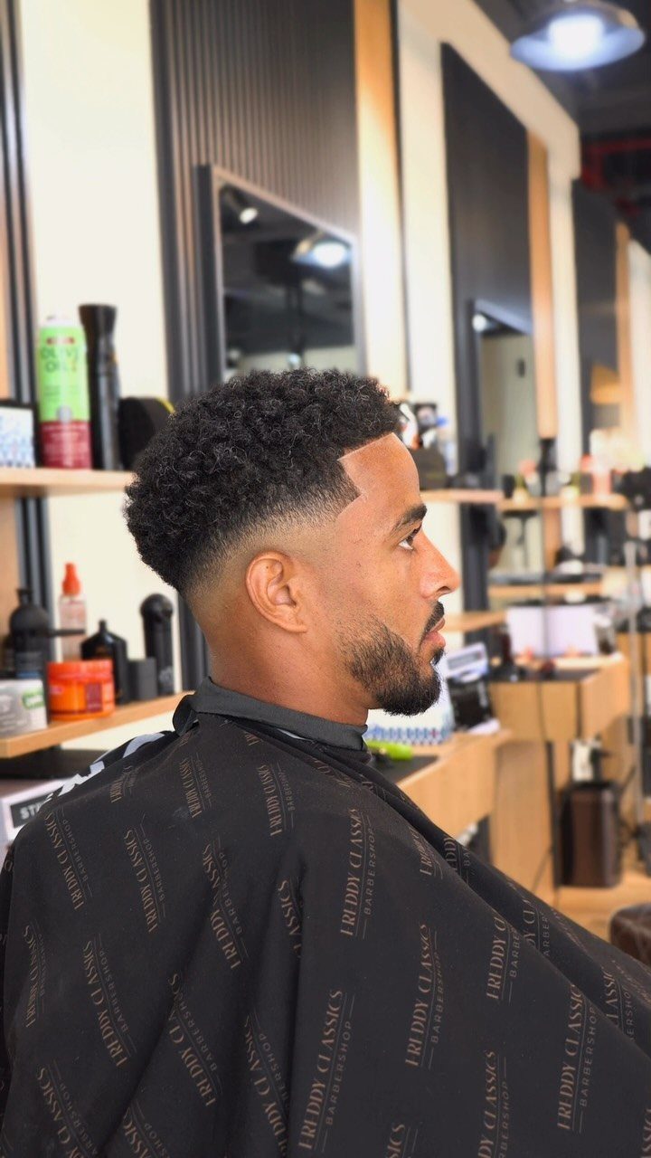 Man with curly hair and a skin fade haircut in a barbershop.