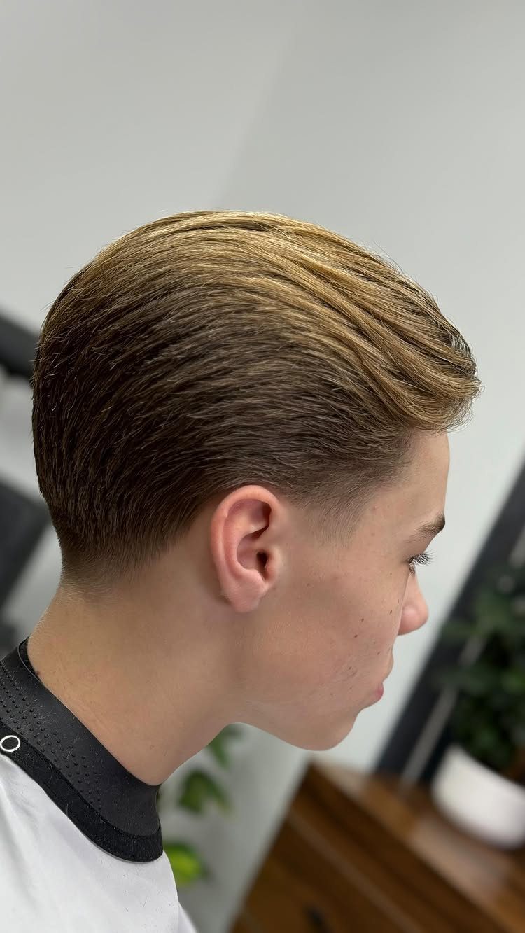 Young man with light brown hair styled in a slick back haircut side profile