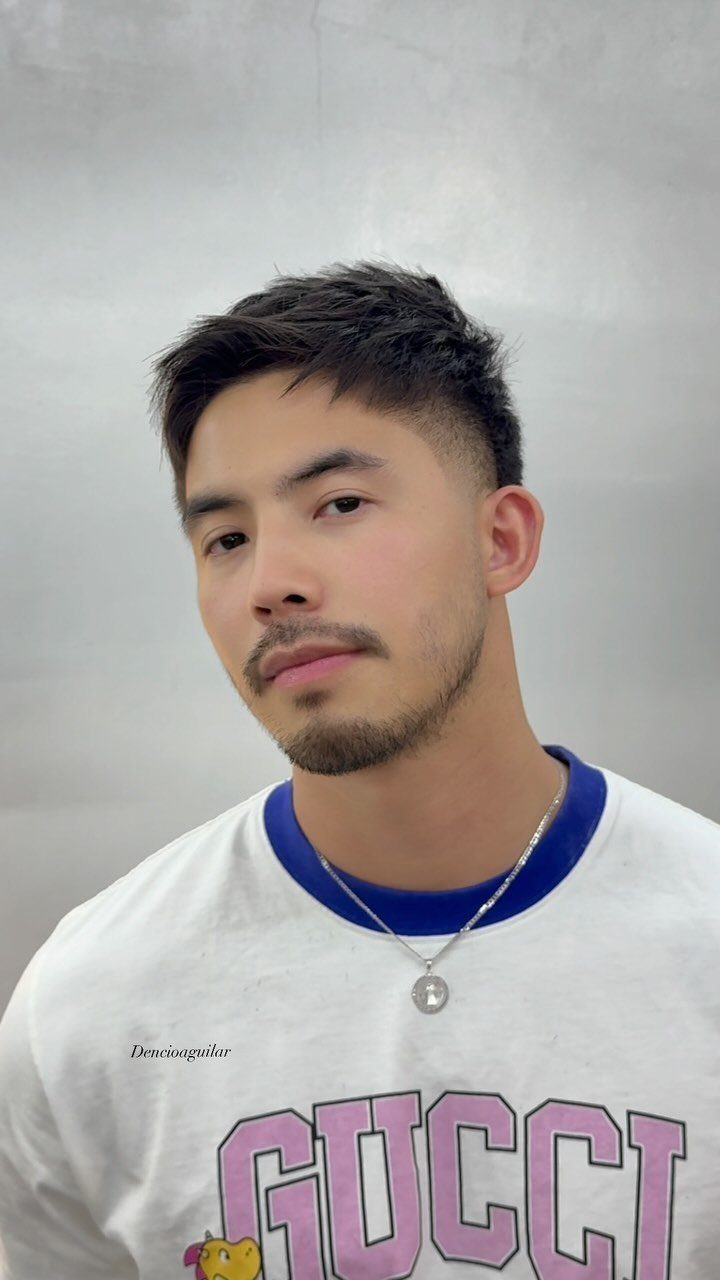 Young man with a short textured taper haircut and groomed facial hair.