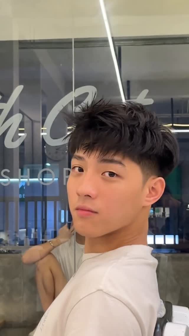 Young man with textured dark hair and a side fade in a barbershop