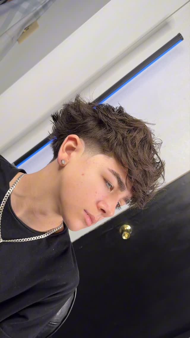 Young man with a textured brown haircut featuring faded sides and voluminous top.