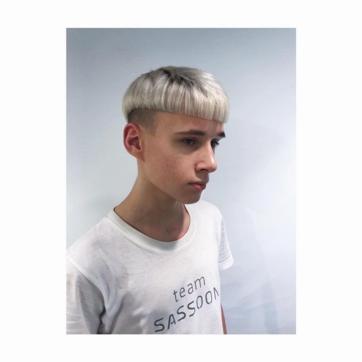 Young man with a bleached blonde bowl cut and blunt fringe.