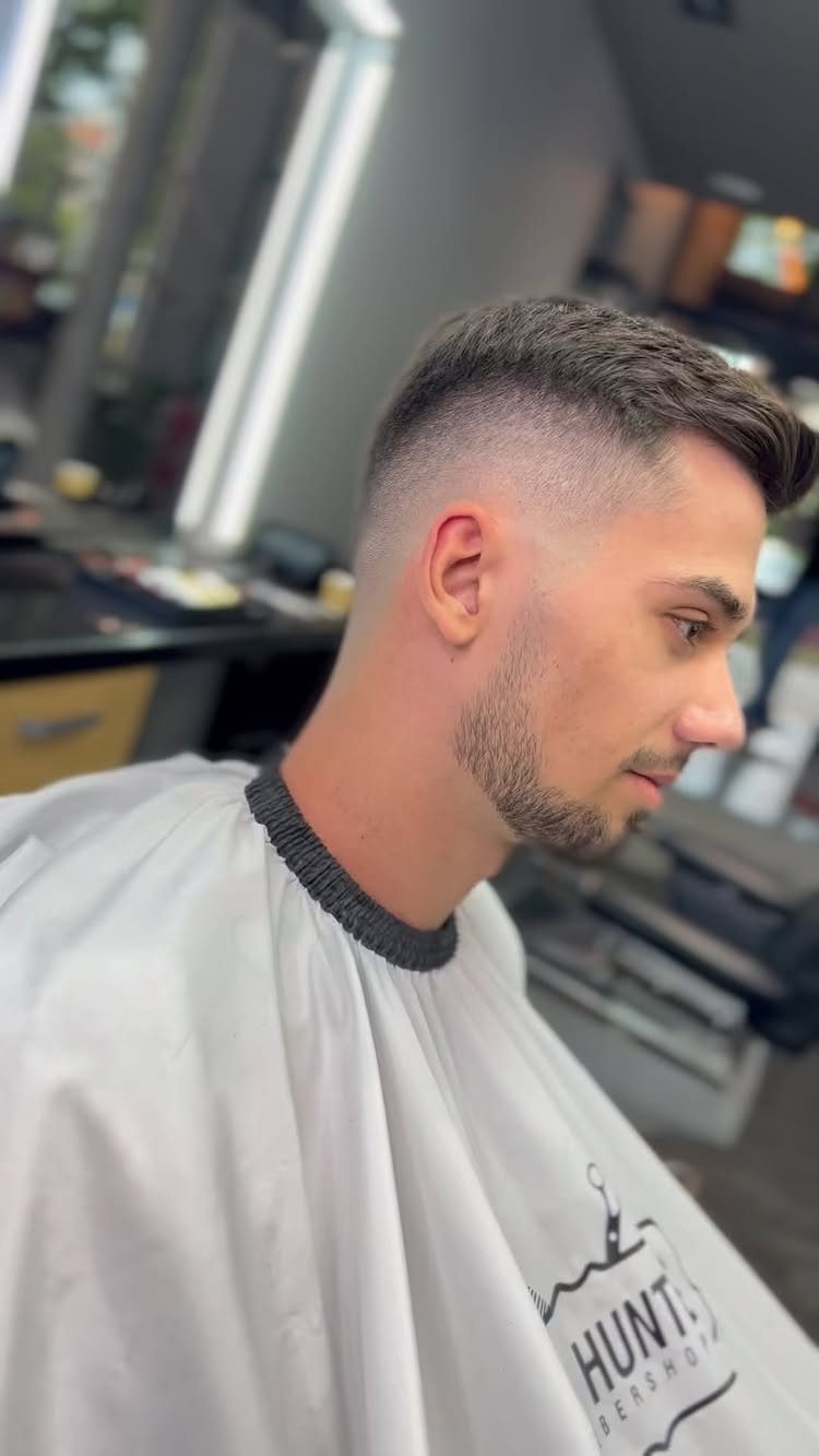 Man with a short crew cut and high skin fade in a barbershop