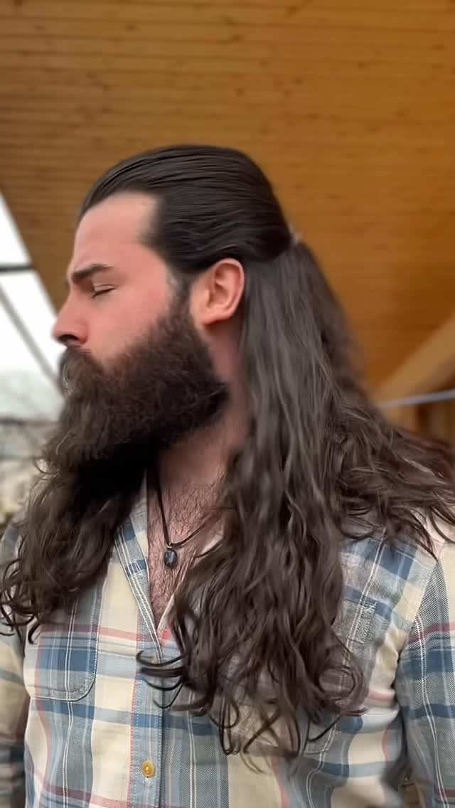 Man with long wavy brown hair tied in a half-up half-down style.