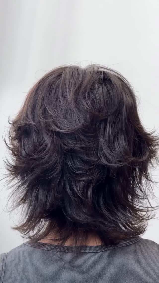 Dark brown layered shag haircut with voluminous choppy ends seen from behind.