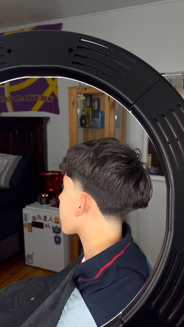 Young man with a low taper fade and textured straight hair on top.