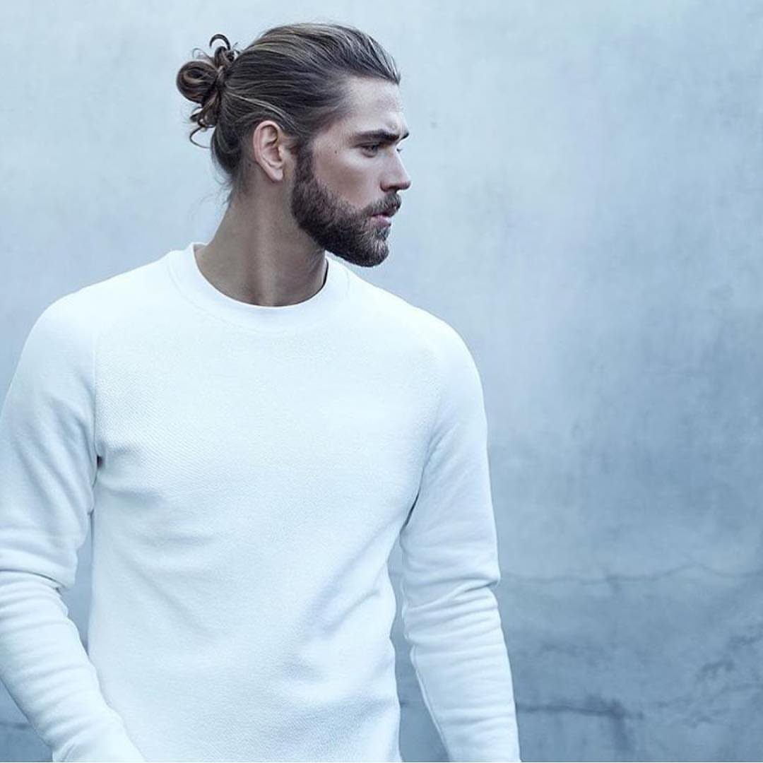 Man with a beard and long brown hair tied in a man bun.