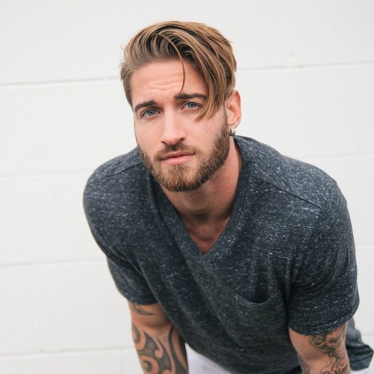 Man with light brown straight hair styled in a neat side part and beard.