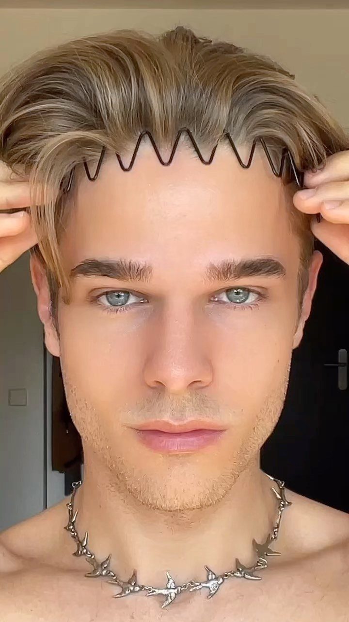 Young man with blonde straight hair wearing a black zigzag hair accessory.