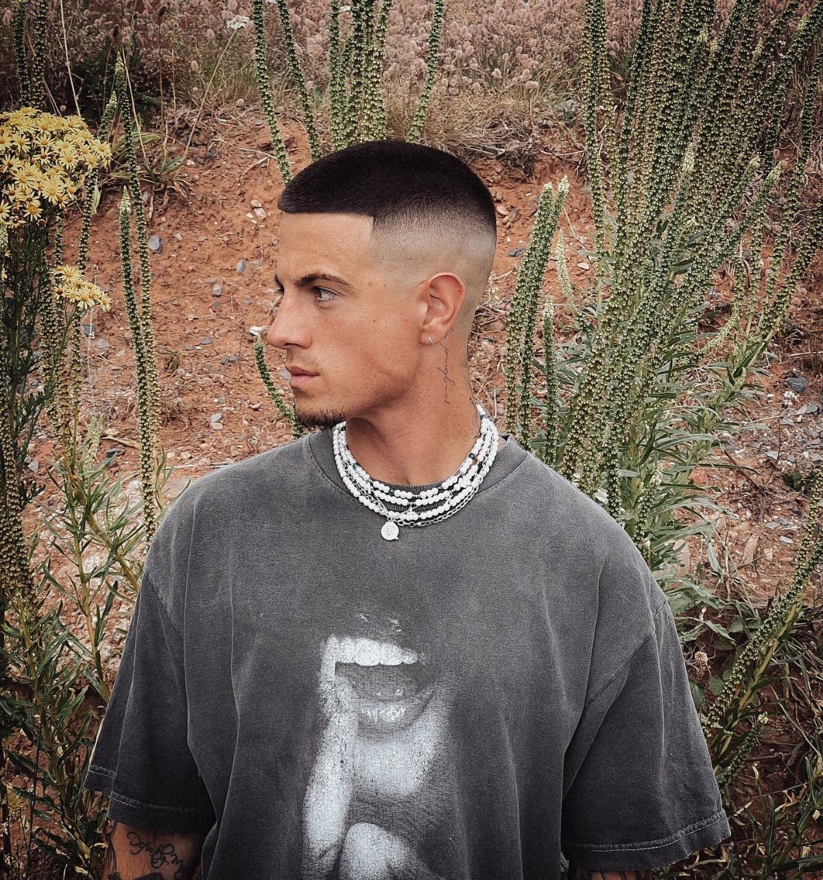 Man with a short buzz cut and high skin fade standing outdoors.