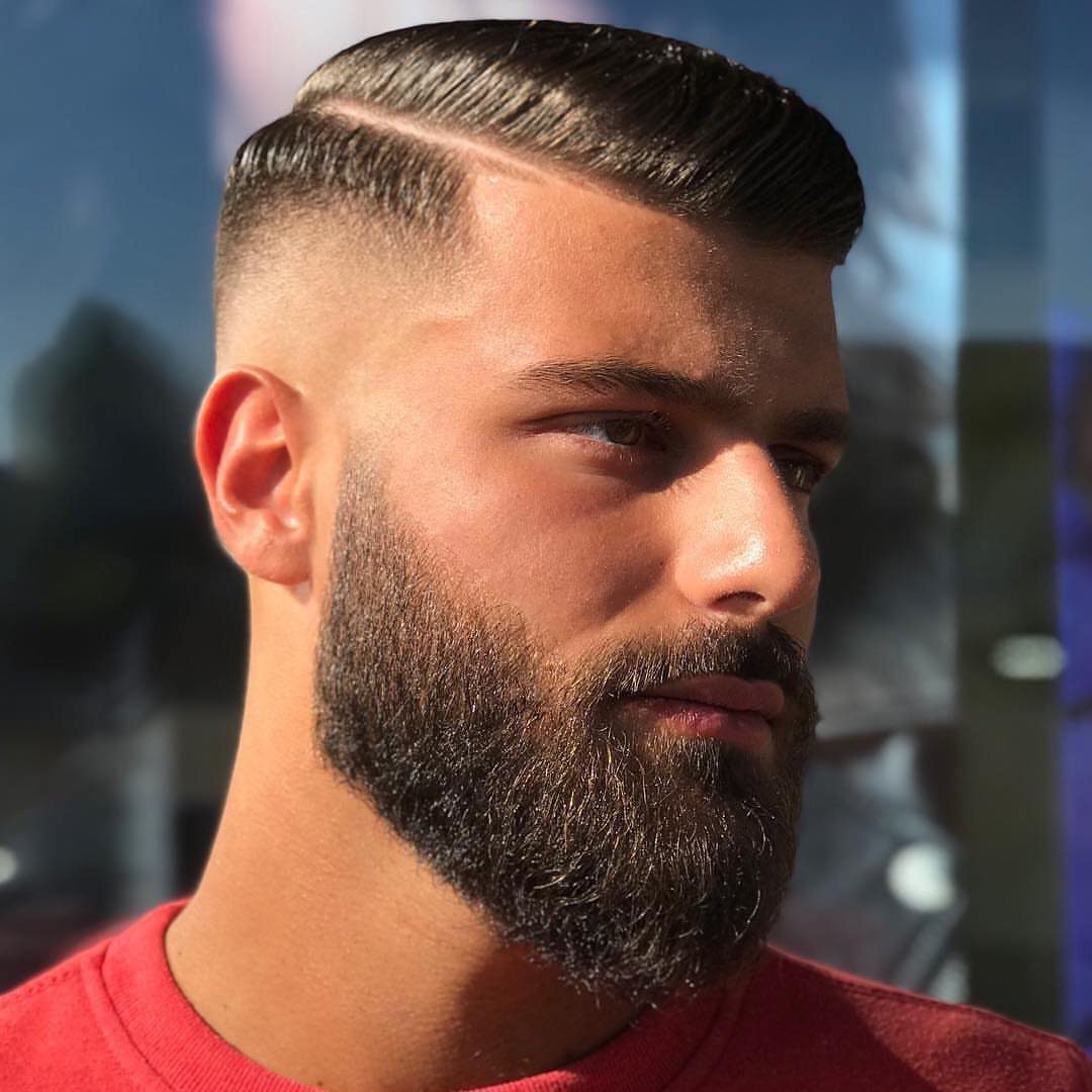 Man with a comb over fade haircut and a full groomed beard