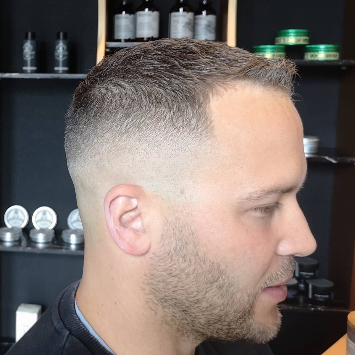 Man with a short crew cut and high skin fade in a barbershop.