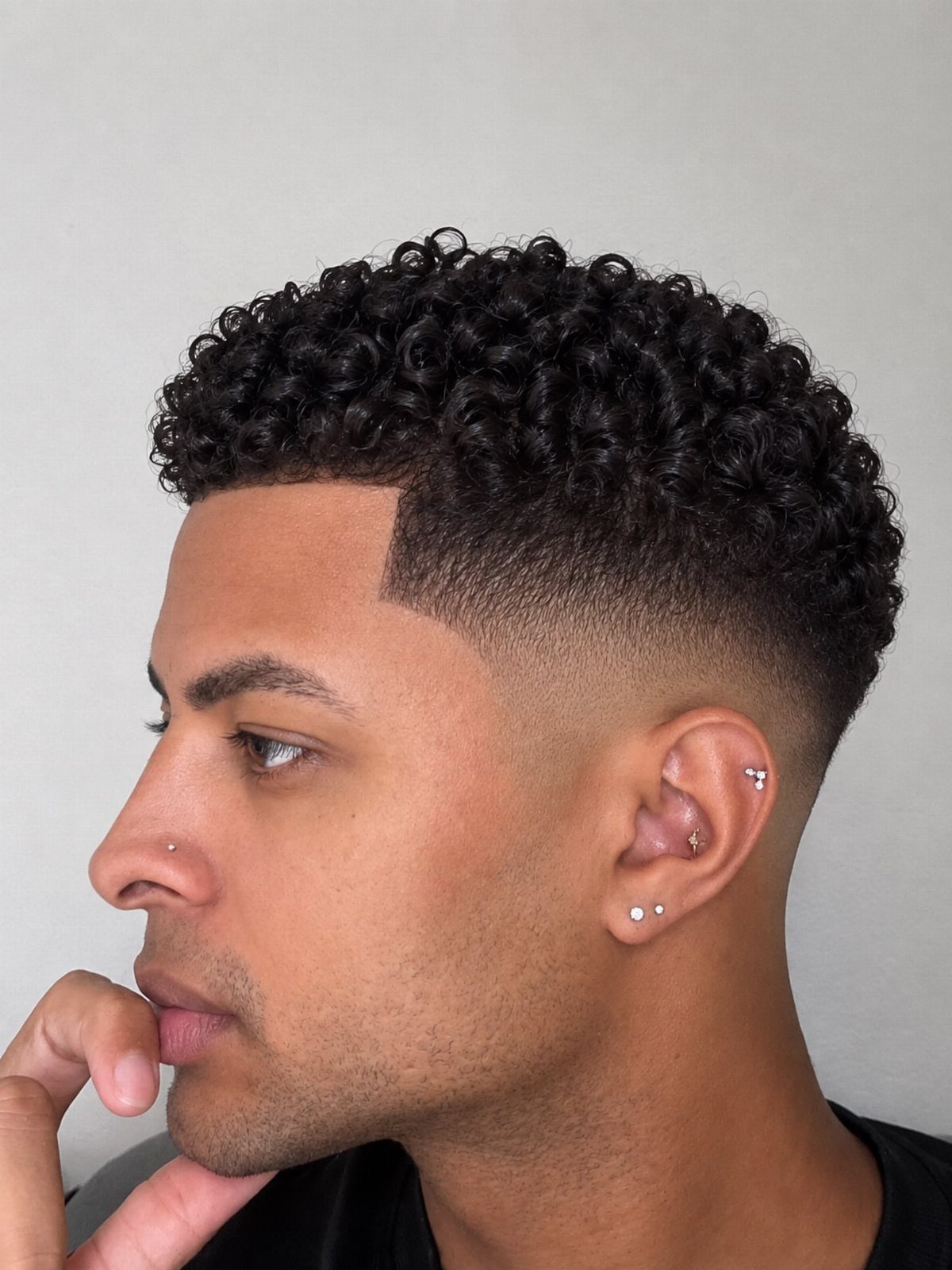 Man with tight curly hair on top and a high skin fade haircut.