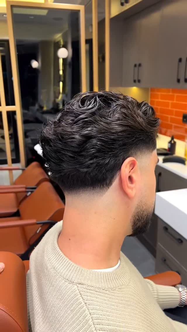 Man with wavy dark hair and a skin fade haircut in a salon