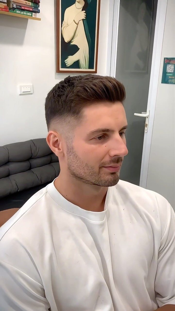 Man with a quiff haircut featuring faded sides and styled upward front hair.