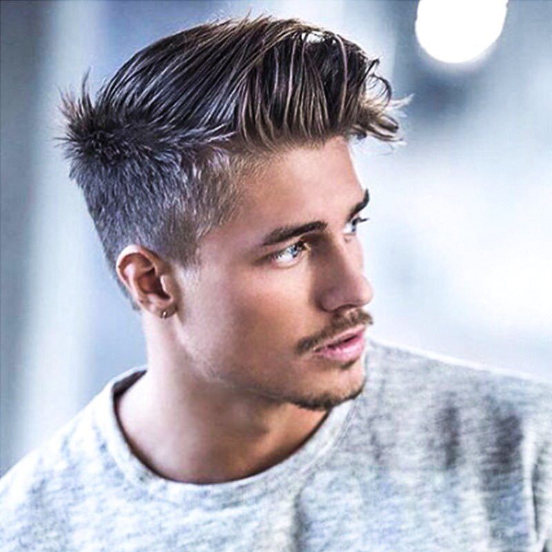 Man with a short brush up haircut and faded sides wearing grey shirt
